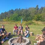 Grupa młodzieży siedząca przy ognisku_ w tle kompleks lasu.jpg